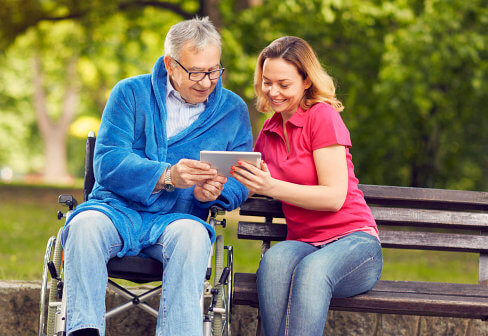 senior and caregiver looking on tablet device